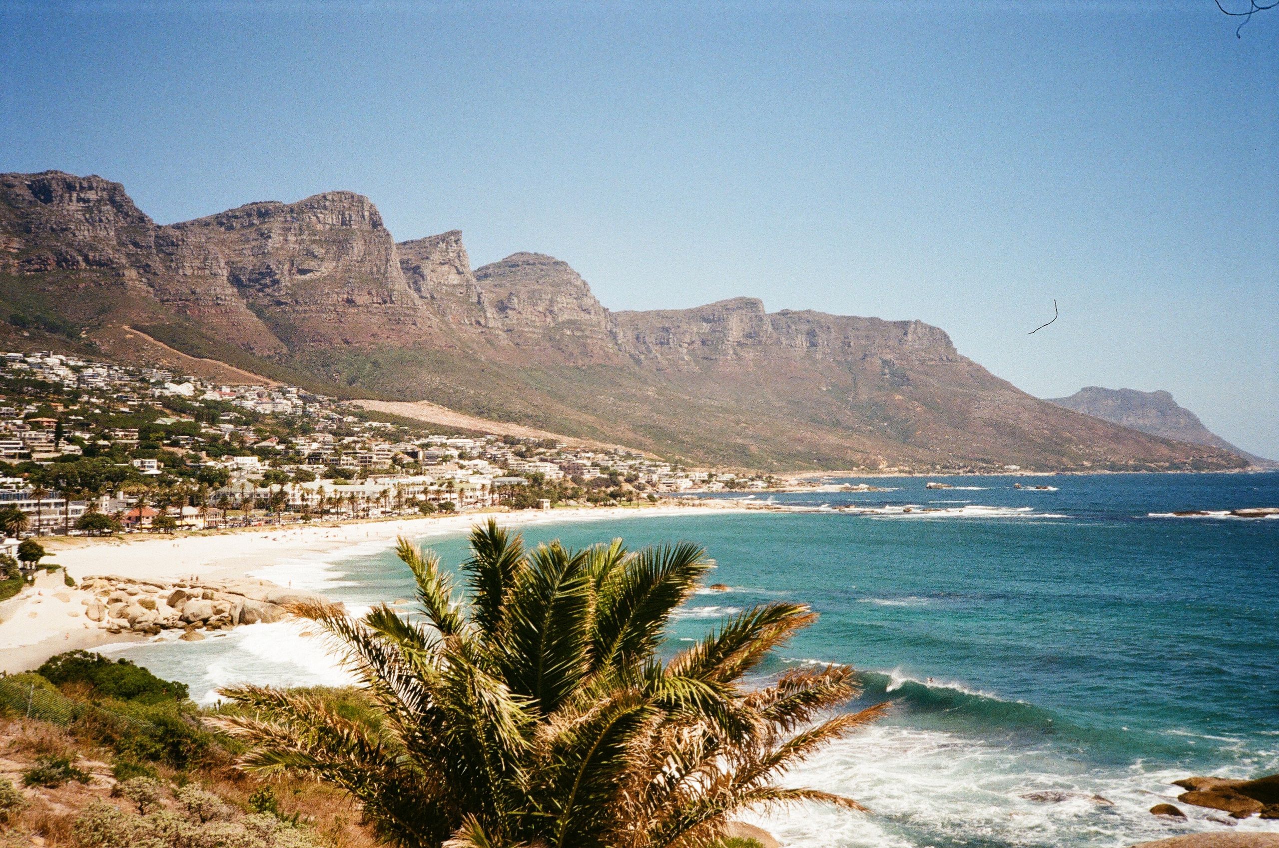 A breathtaking seaside view of Camps Bay and the Twelve Apostles mountains in Cape Town, South Africa and where to stay in Cape Town.