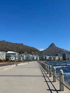 Beautiful view of Cape Town promenade with Lion's Head in the backdrop under clear blue skies.